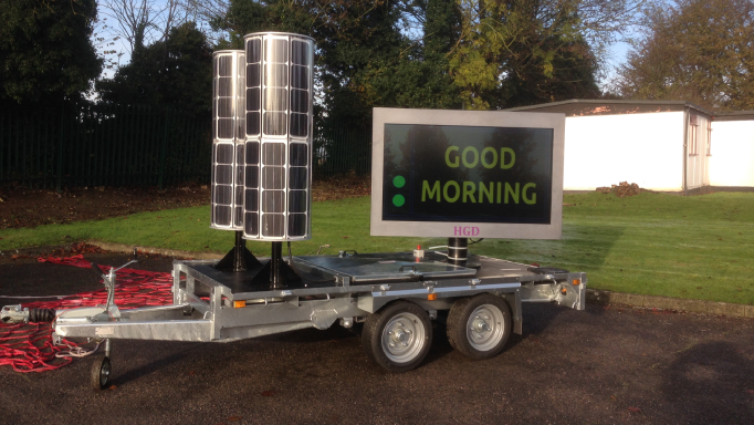 Mobile solar-powered sign displaying 'GOOD MORNING' outdoors.