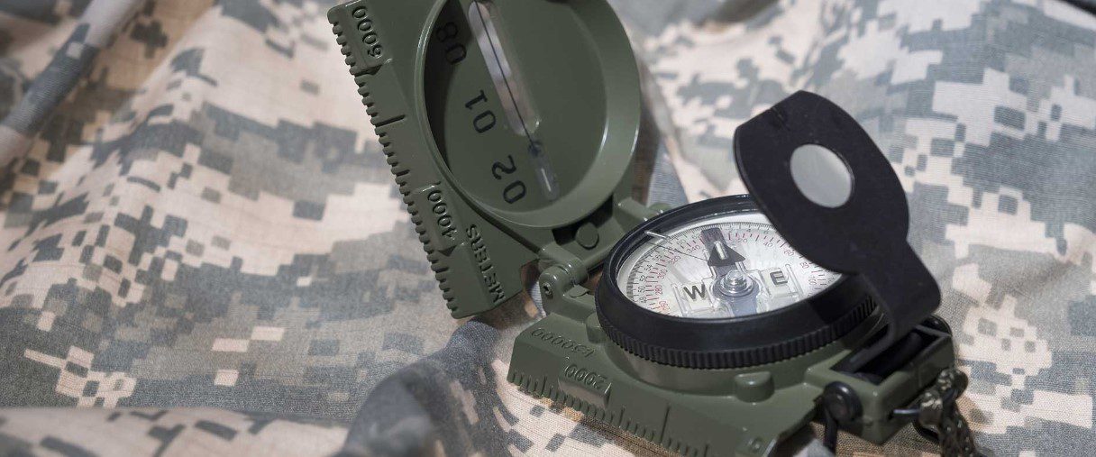 Close-up of a military-style compass on camouflage fabric.