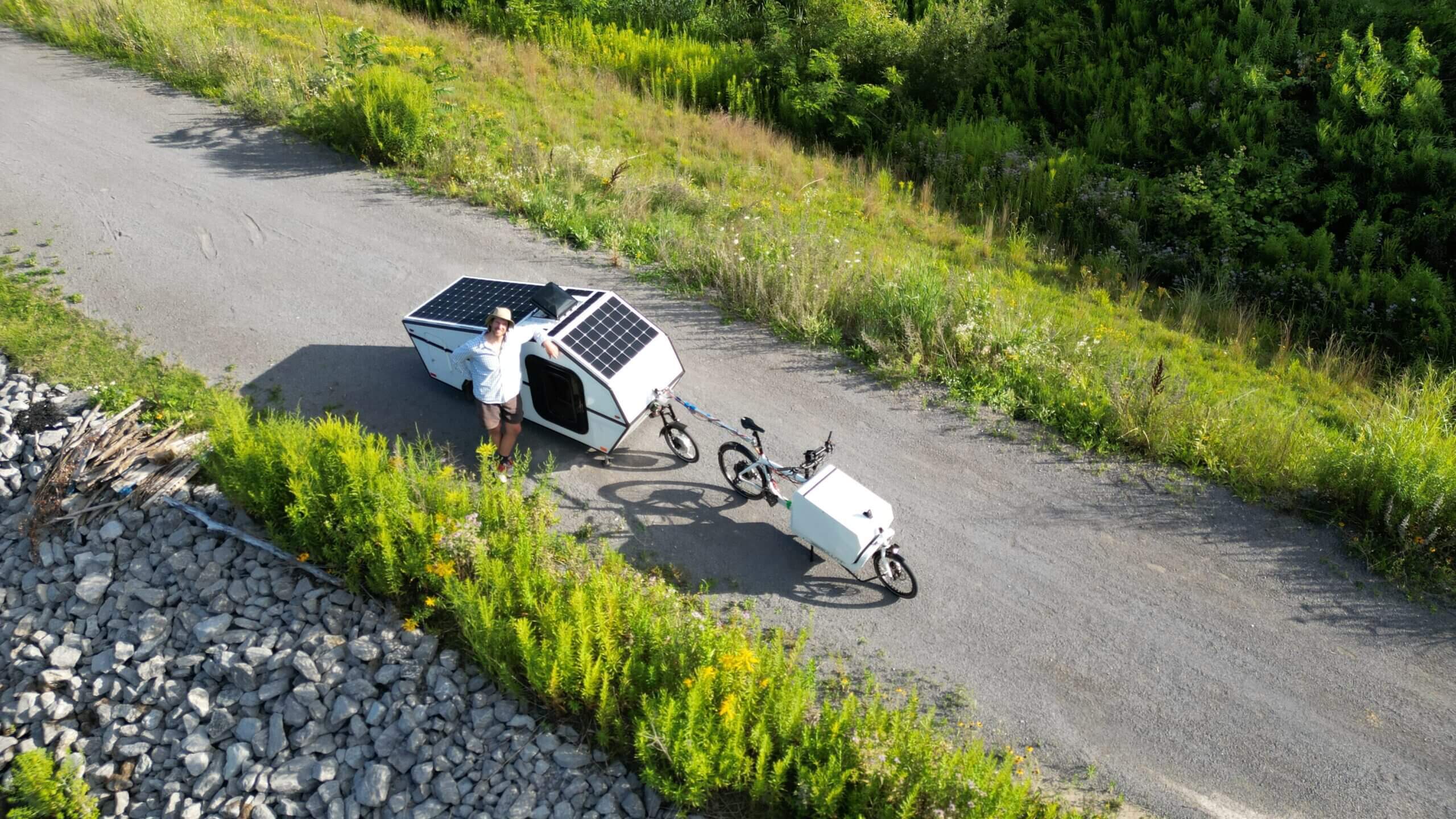 Two people riding cargo bikes on a paved path surrounded by greenery.